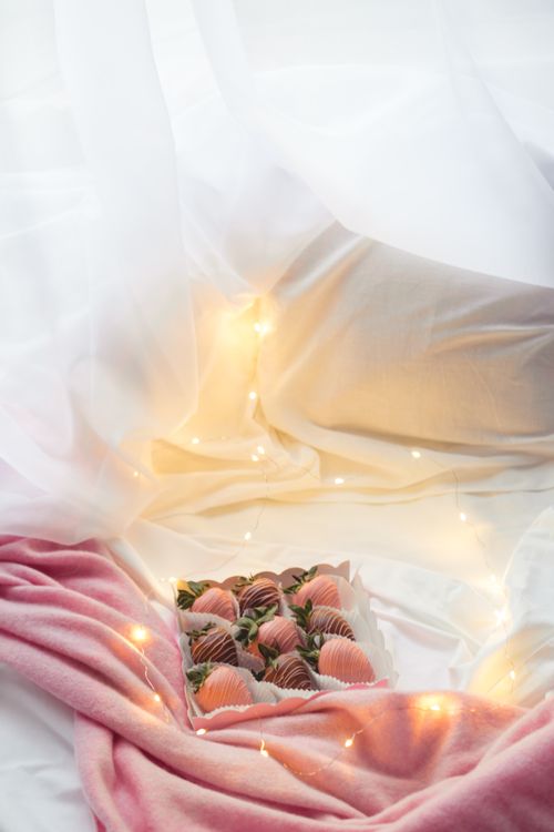 Free A luxurious arrangement of chocolate-covered strawberries surrounded by soft fabrics and ambient lighting. Stock Photo