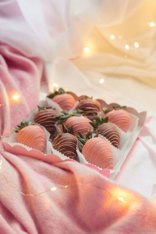 Free Delicious chocolate-covered strawberries elegantly boxed with romantic string lights. Stock Photo