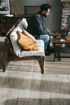 A man working remotely from a stylish living room setting with a laptop.