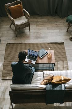 A person working remotely in a stylish living room, featuring a laptop and modern decor.