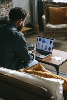 Man using laptop for online shopping from home, viewing clothing options.