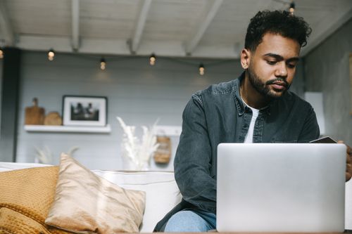 Free Focused young man working remotely on a laptop in a cozy indoor setting. Stock Photo