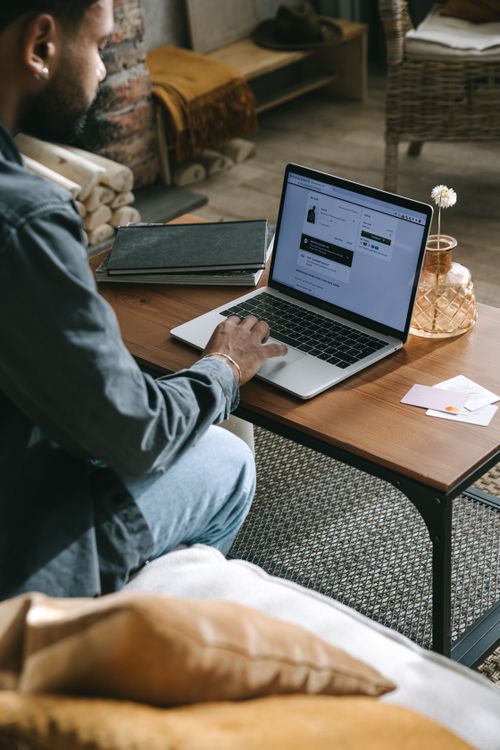 Free A man working remotely on a laptop in a cozy, minimalist home office setting with warm tones. Stock Photo