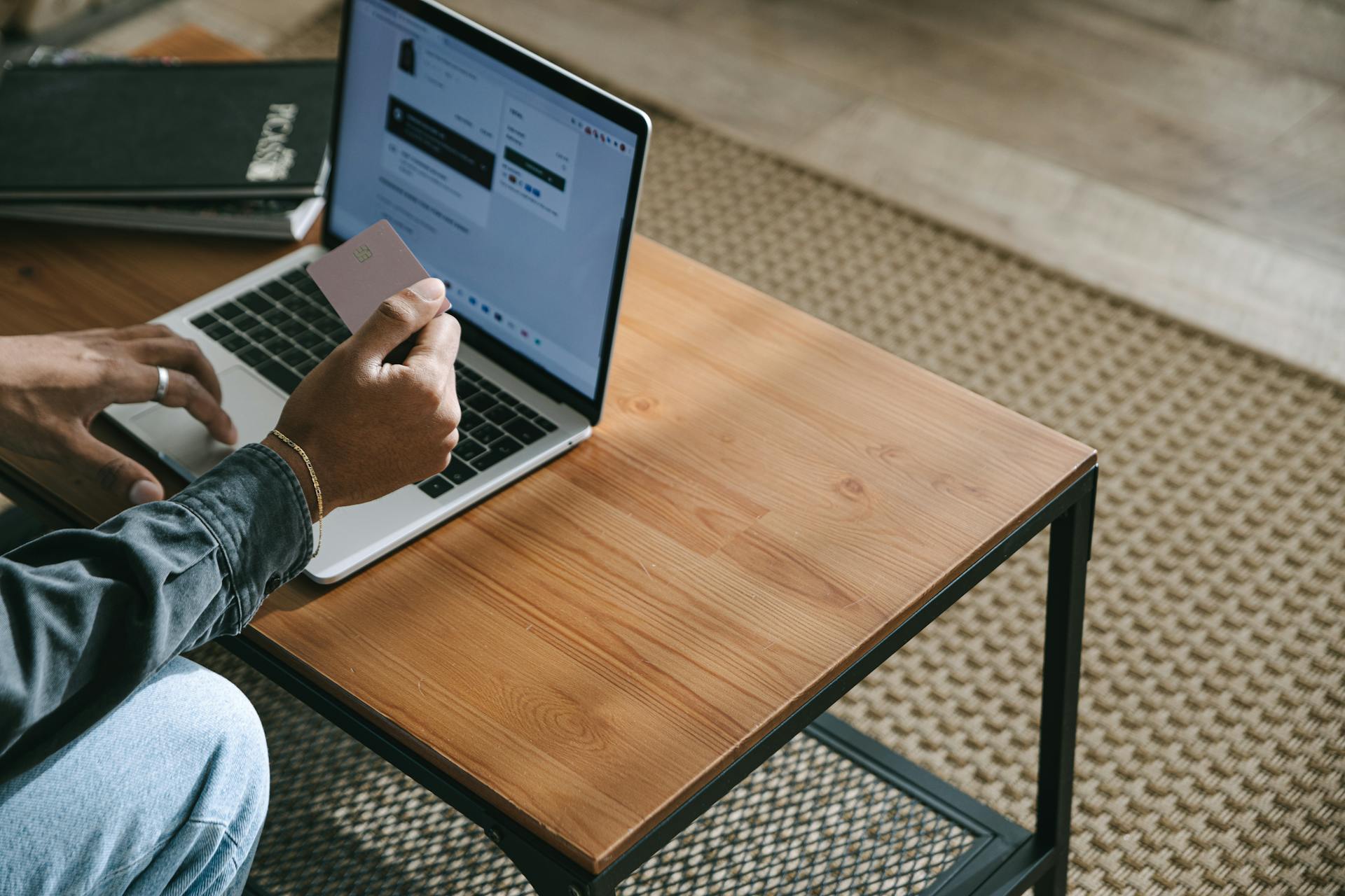 A Person Holding a Credit Card while Using a Laptop