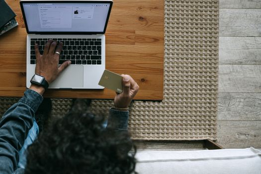 Overhead view of a person using a laptop and credit card for online shopping.