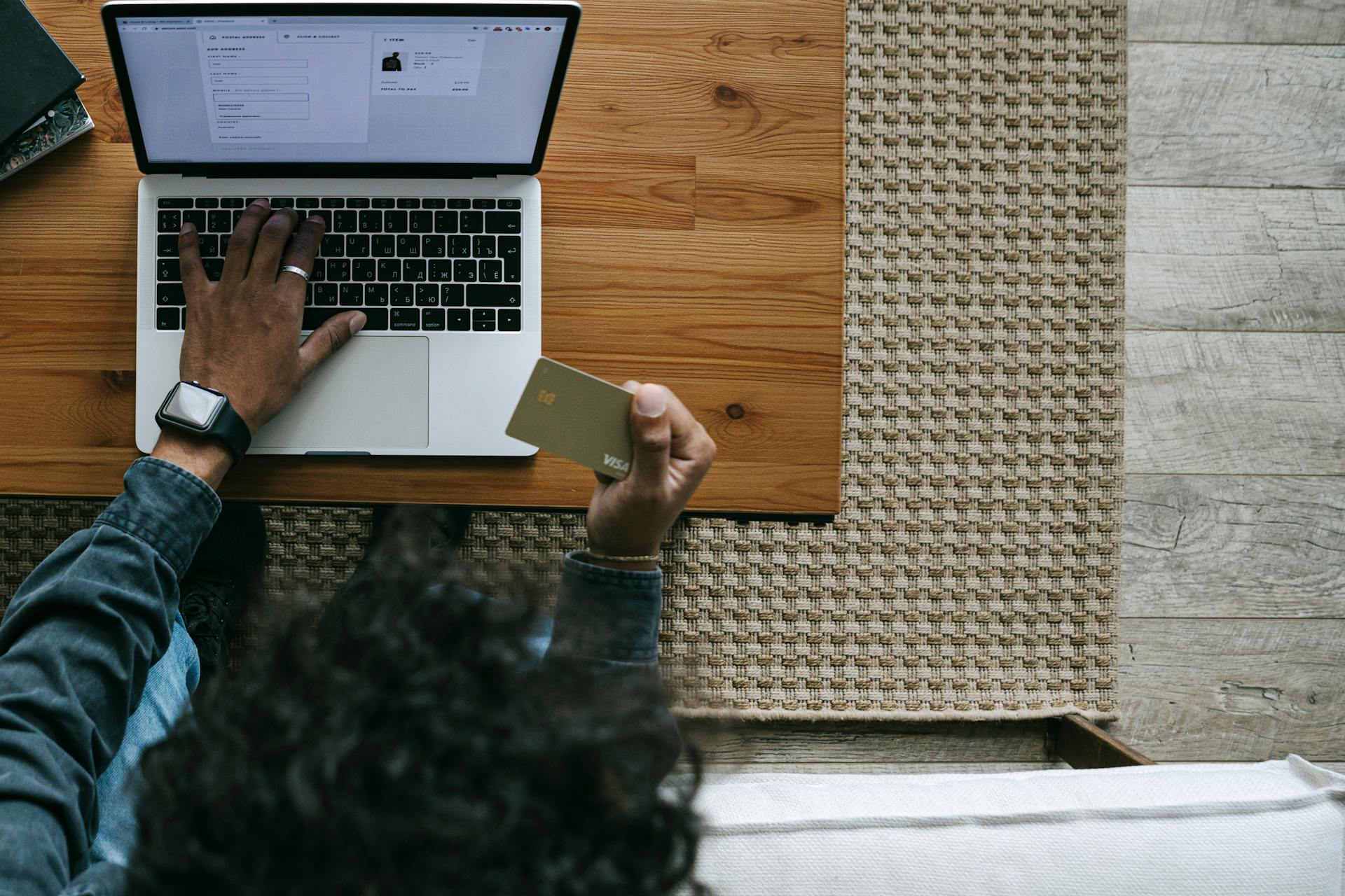 Overhead view of a person using a laptop and credit card for online shopping.