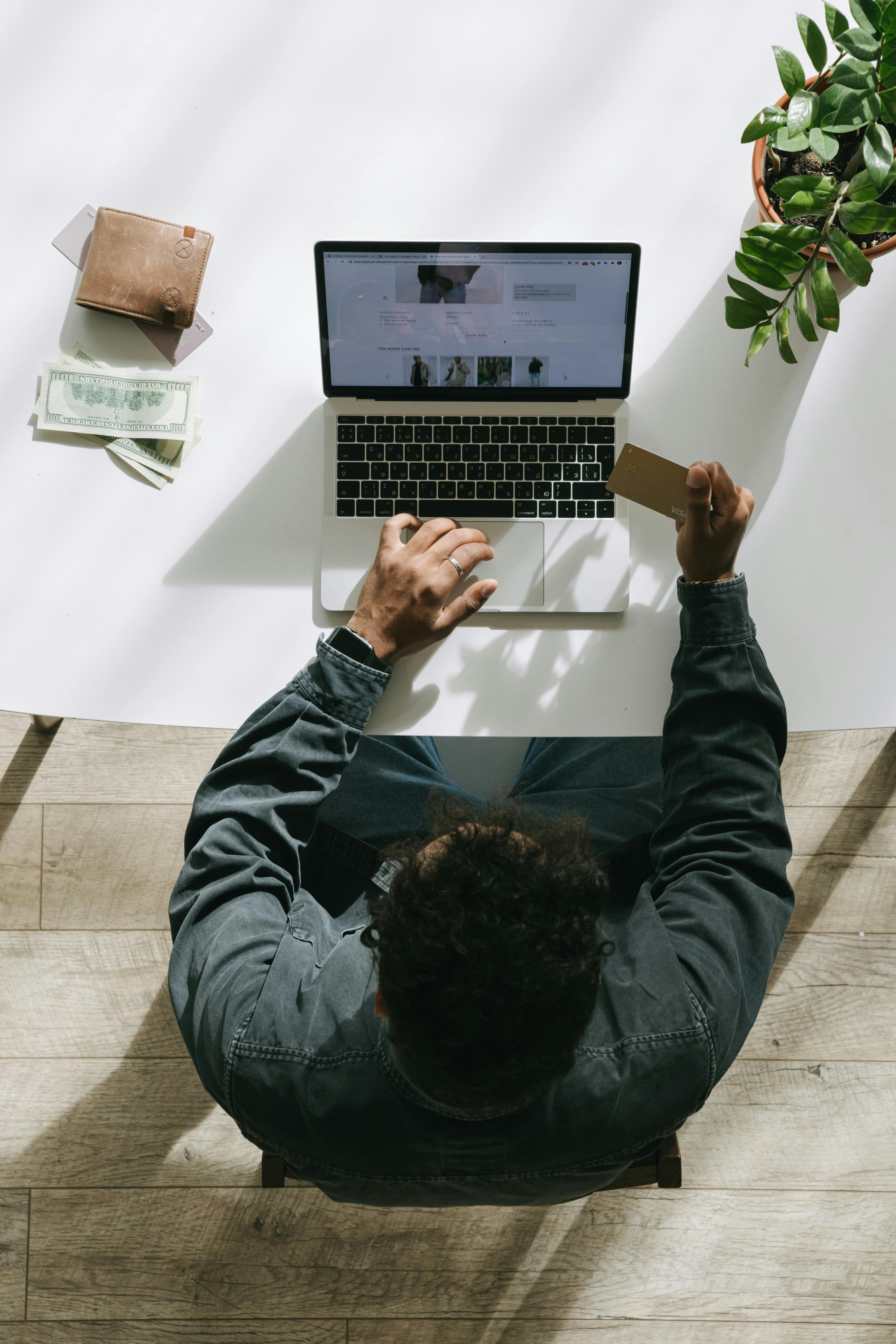 Overhead view of man using laptop and credit card for online shopping.