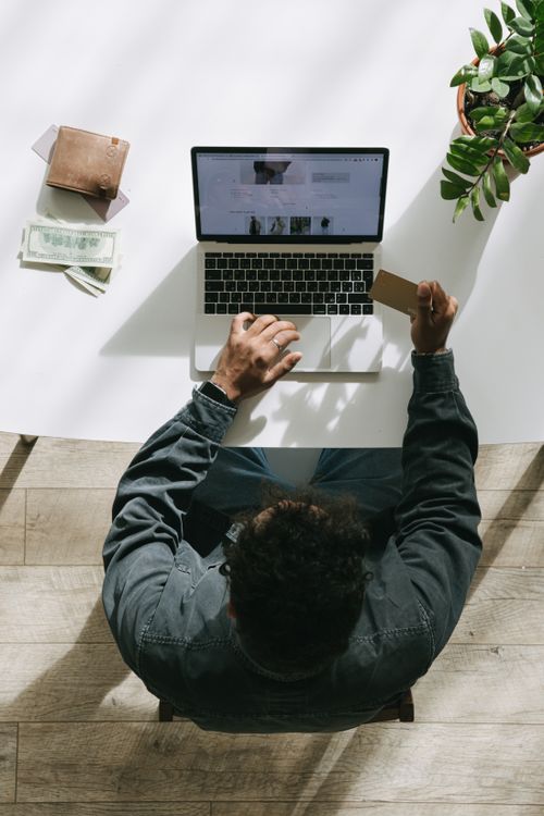Free Overhead view of man using laptop and credit card for online shopping. Stock Photo