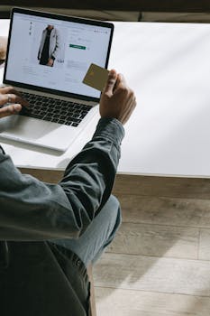 Person using a credit card to shop online on a laptop at home.