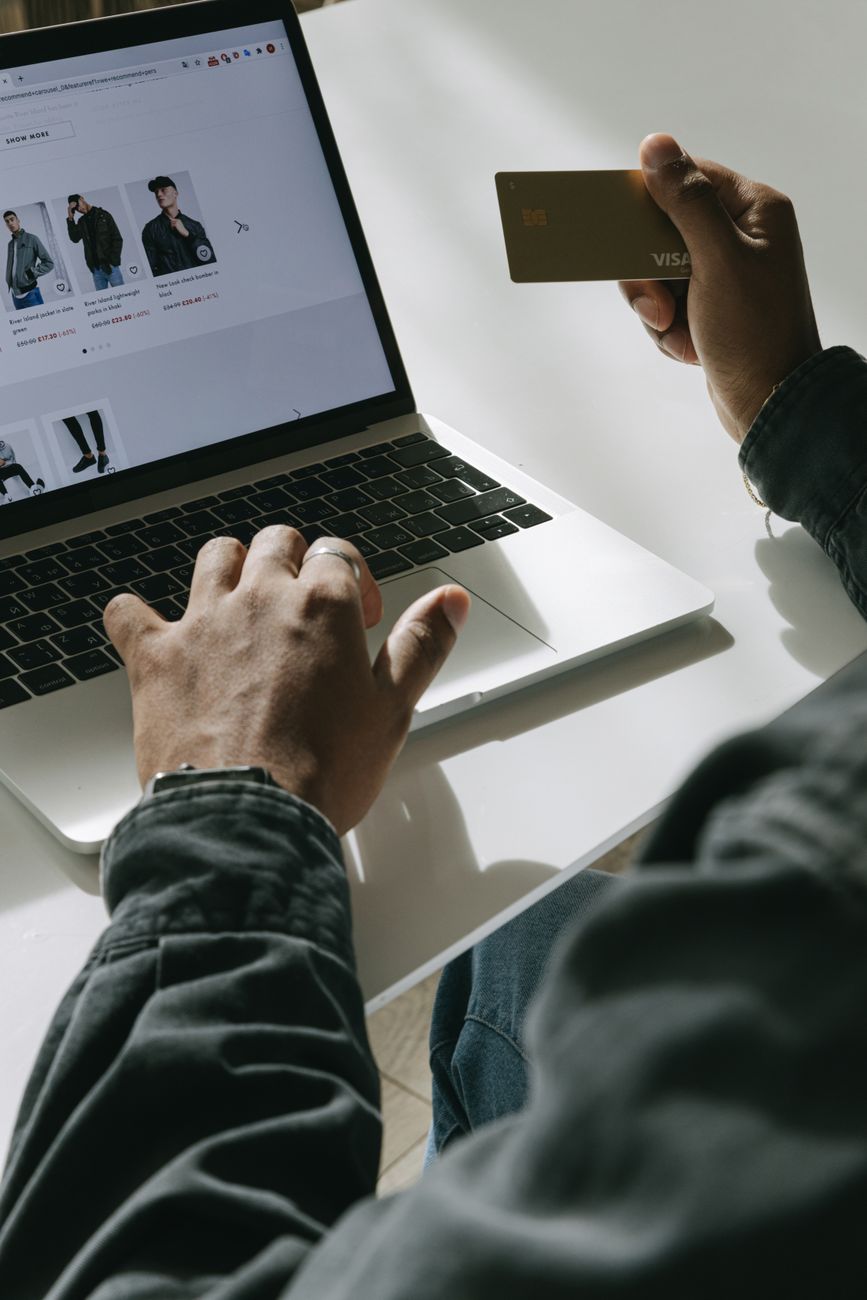 Persoon die online winkelt met een creditcard op een laptop in een heldere omgeving.