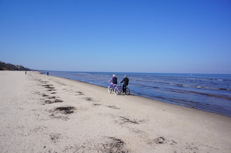 
A Couple Riding A Bicycle On The Beach