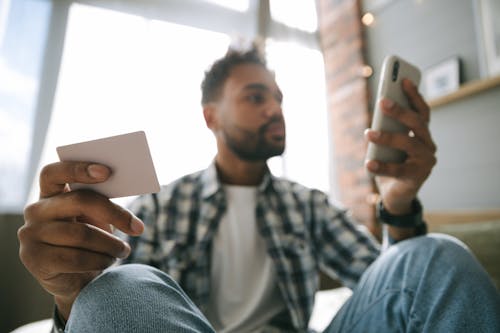 Free Close Up Photo of a Man Holding Cellphone and a Card Stock Photo