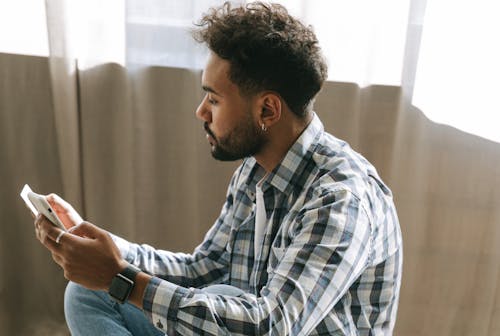 A Man in Plaid Long Sleeves Looking at the Debit Card He is Holding