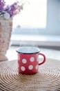 一个红色圆点杯热气腾腾地放在纹理编织垫上，营造出舒适的氛围