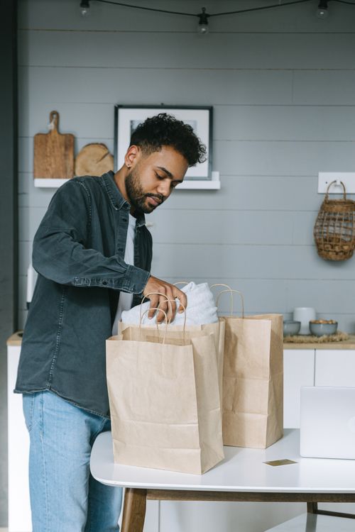 A Man in Gray Long Sleeves Unpacking Paper Bags on the Table · Free ...