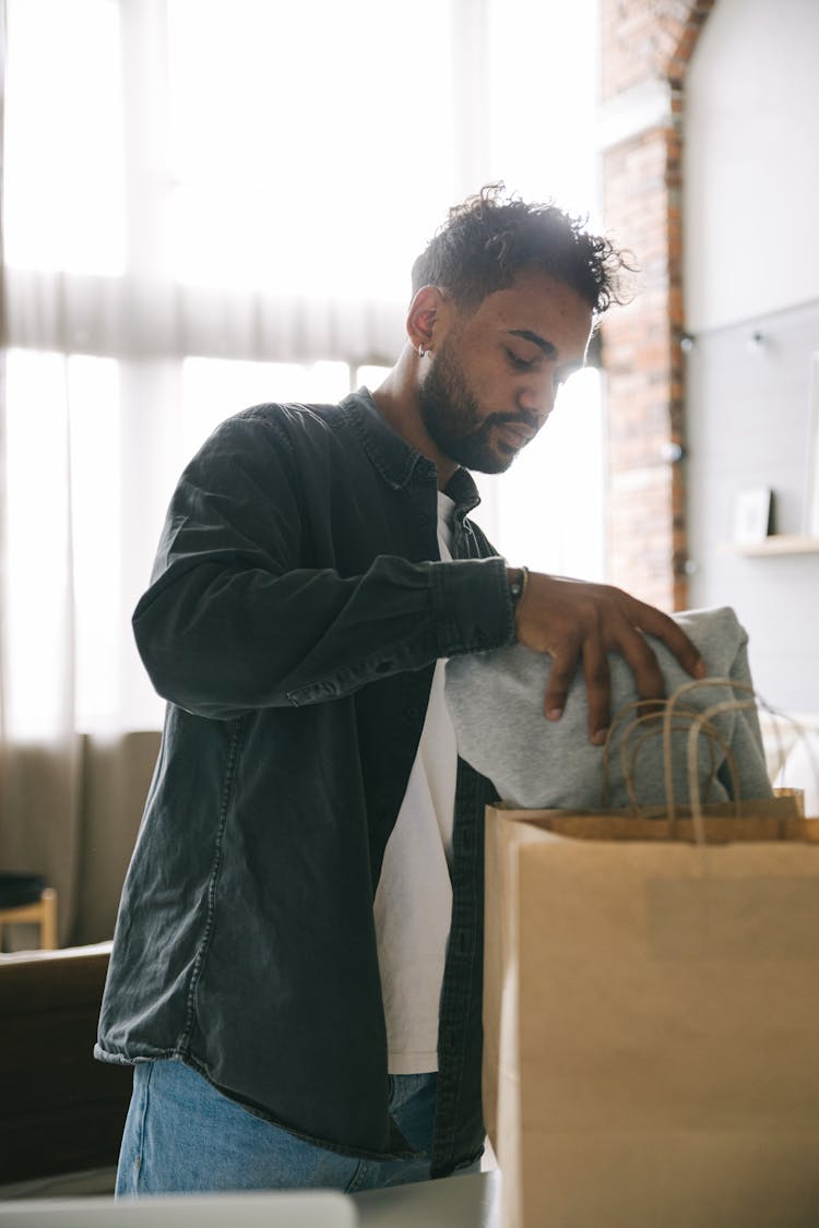 Man Putting Clothing In A Paper Bag