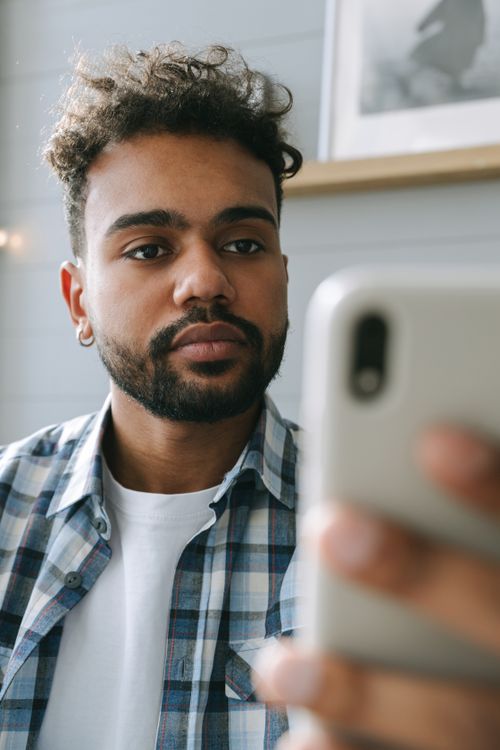 Free Close-up portrait of a bearded man using a smartphone indoors, focused expression. Stock Photo