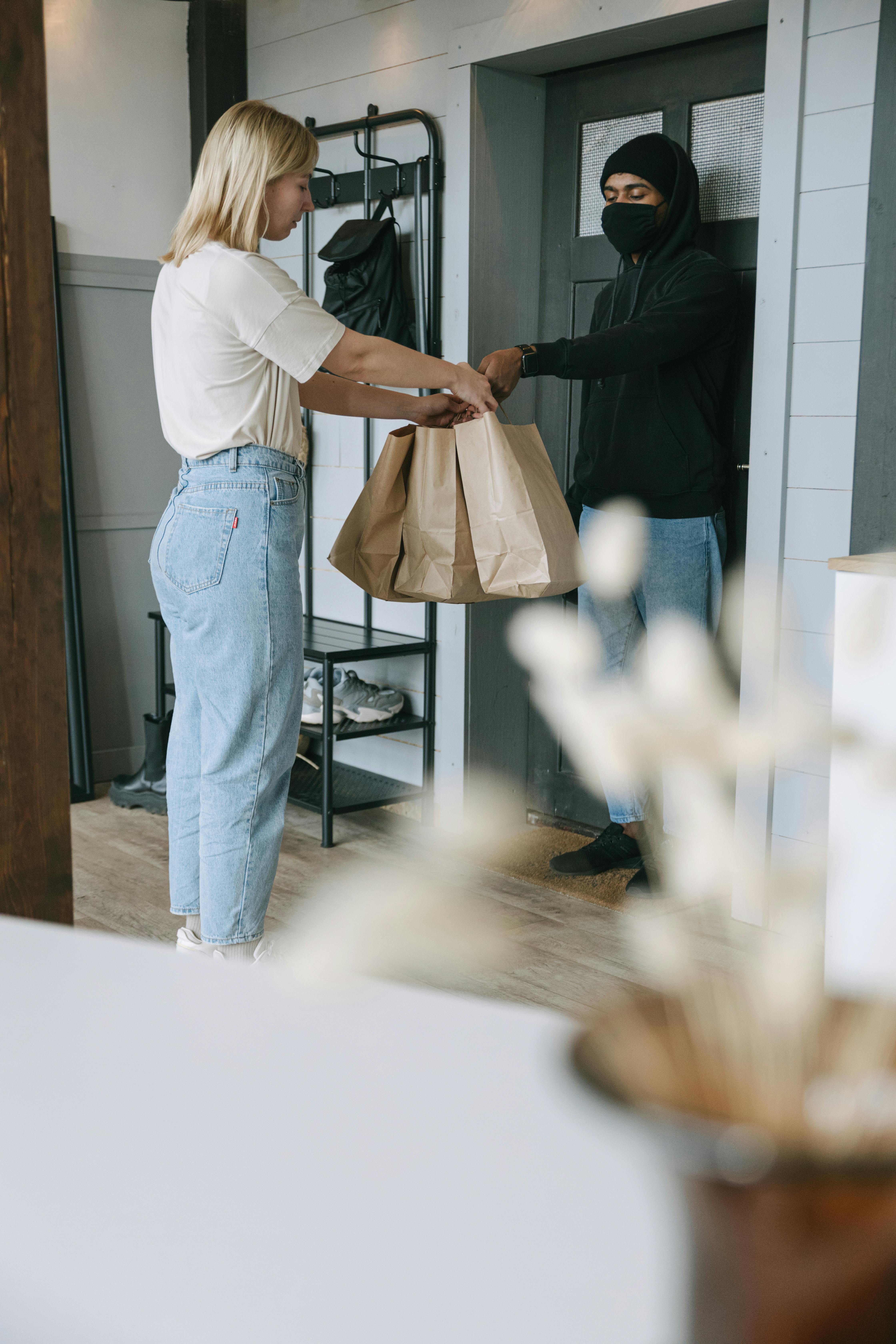 man in white shirt and blue denim jeans holding brown paper bag