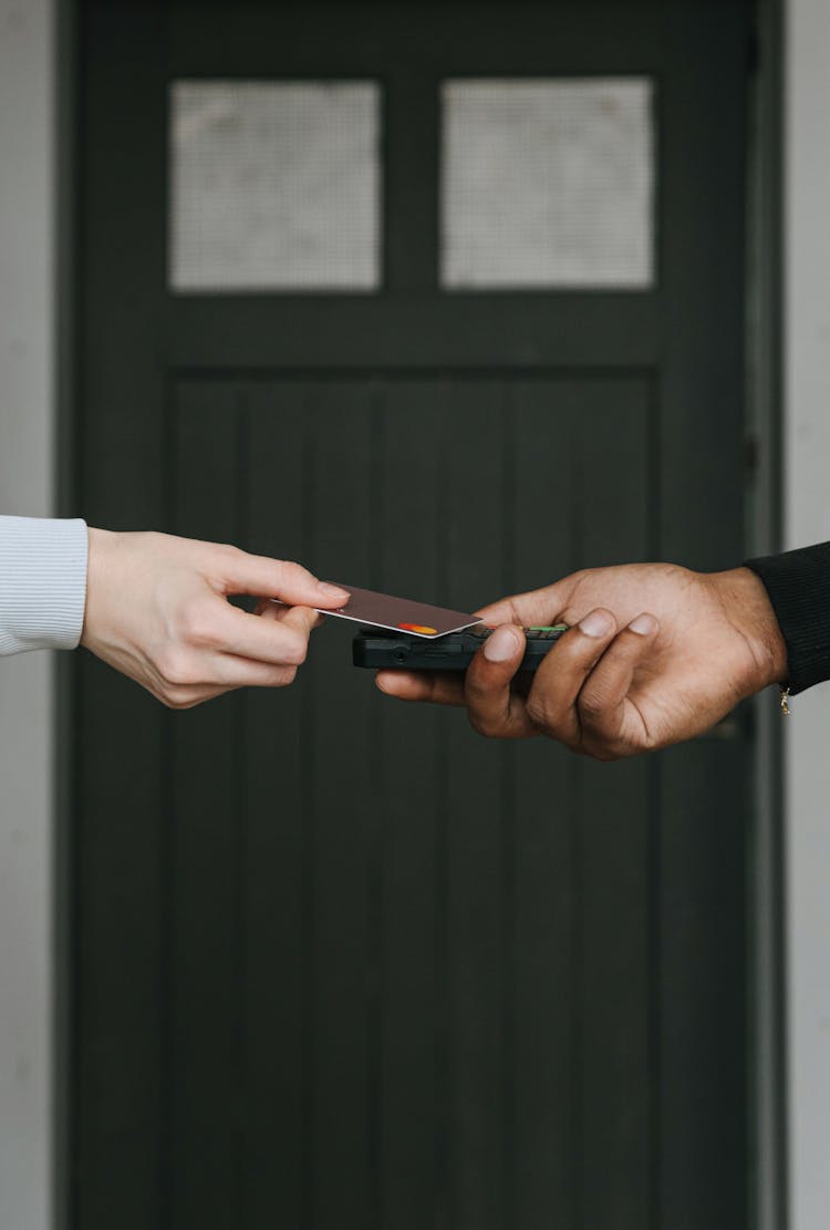 A Person Swiping A Card On A Payment Terminal