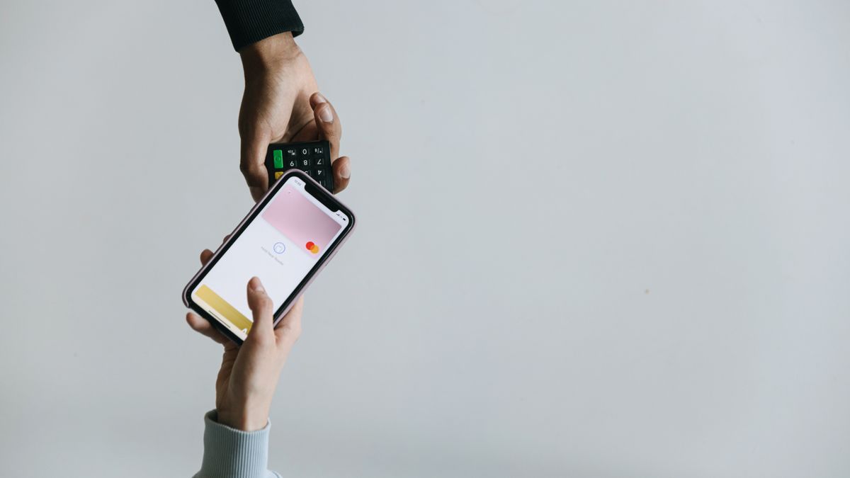 Mãos usando smartphone e maquininha para realizar um pagamento digital sem dinheiro em espécie