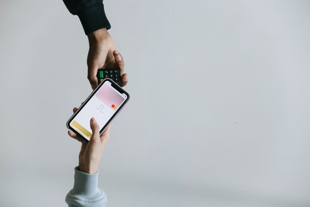 Mãos usando smartphone e maquininha para realizar um pagamento digital sem dinheiro em espécie
