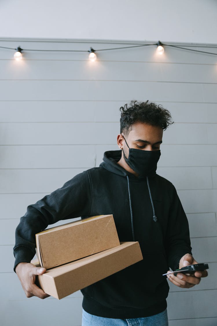 A Man Using A Payment Terminal While Carrying Packages