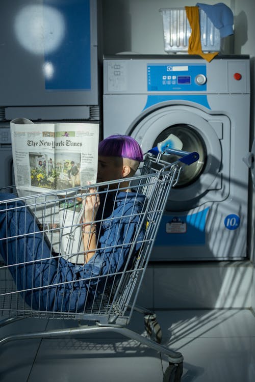 Woman reading Newspaper in a Shopping Cart