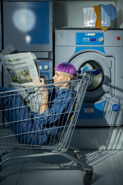 Woman reading Newspaper in a Shopping Cart
