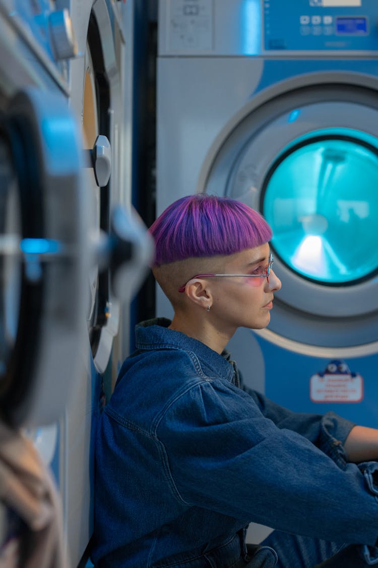 Woman In Violet Hair Leaning On A Laundry Machine