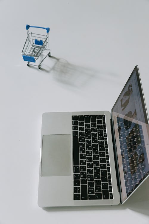 Free 
A Laptop beside a Miniature Shopping Cart Stock Photo