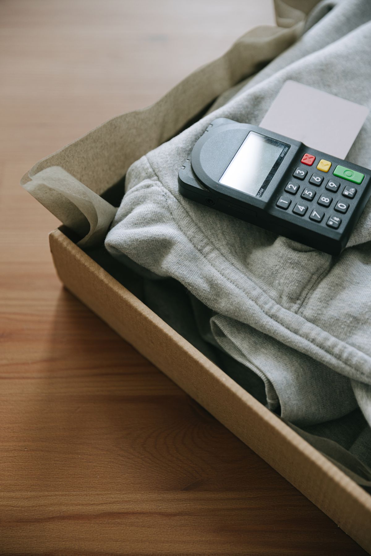 Payment terminal placed beside folded clothing and a parcel