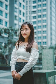 Young woman in stylish attire posing outdoors with urban background.