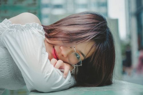 Free Close-up portrait of a young woman in a white blouse with eyeglasses, resting thoughtfully. Stock Photo