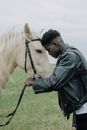 Man in Black Leather Jacket Holding White Horse