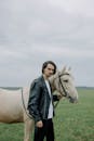 Woman in Black Leather Jacket Standing Beside White Horse