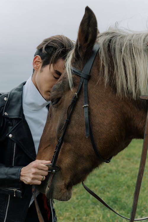 Man In White Turtleneck Shirt And Black Leather Jacket Leaning His Head On  A Horse · Free Stock Photo