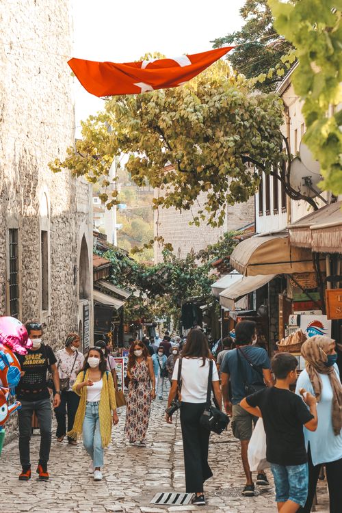 Free Crowded street market in Turkey, vibrant with people and a waving Turkish flag. Stock Photo