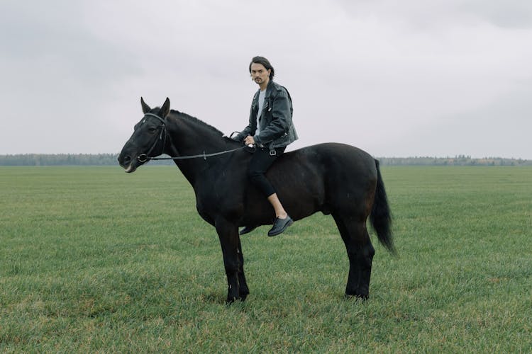 Man Riding A Horse On A Grassy Field