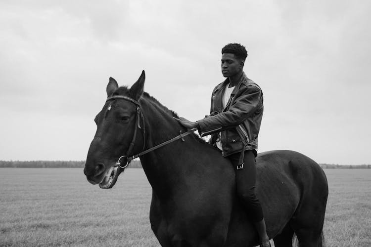 A Man Riding A Horse On A Grass Field