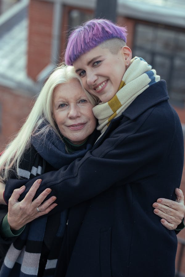 Woman in Black Coat Smiling Beside Woman in Yellow Scarf