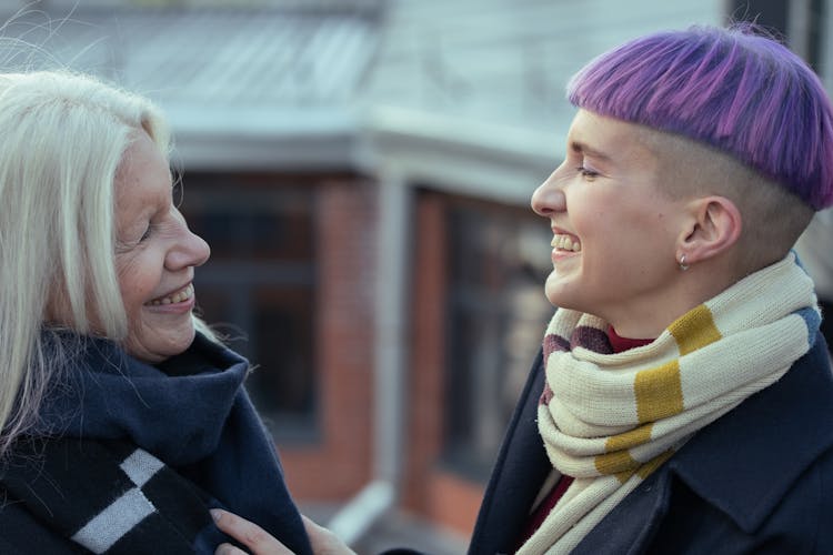 Women Wearing Scarves Smiling At Each Other