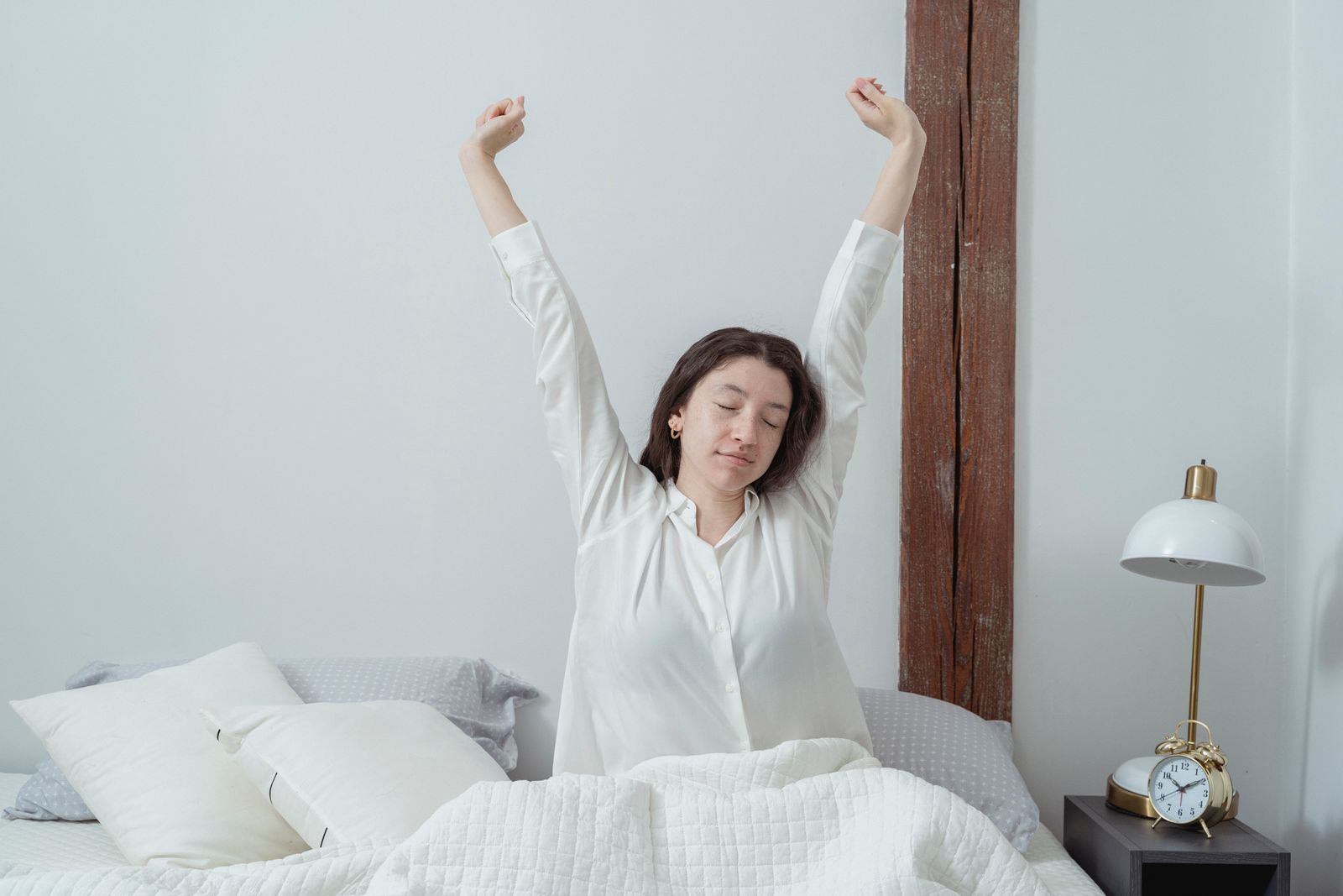 A woman waking up in bed in the morning light, one of the first places the early signs of menopause show up