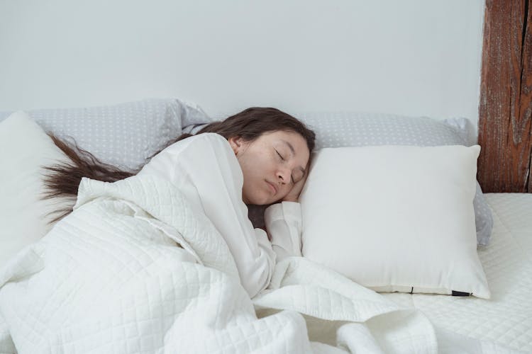 Young Woman Sleeping On White Bed