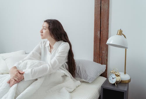 Serene female sitting on bed in morning