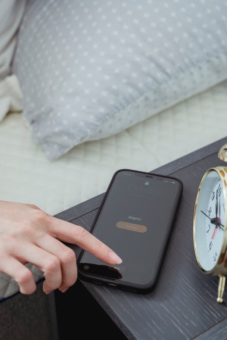 Crop Woman Snoozing Alarm On Smartphone