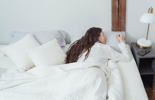 Free Calm woman sleeping on belly on white bed Stock Photo