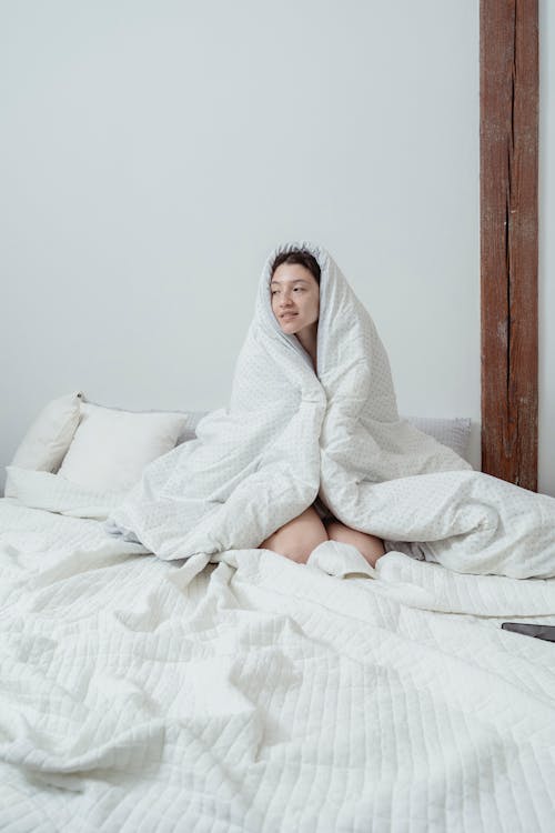 Free Woman with a Blanket Sitting on the Bed Stock Photo