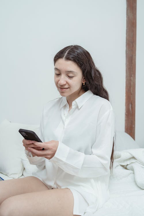 Woman in White Long Sleeves Using a Cellphone
