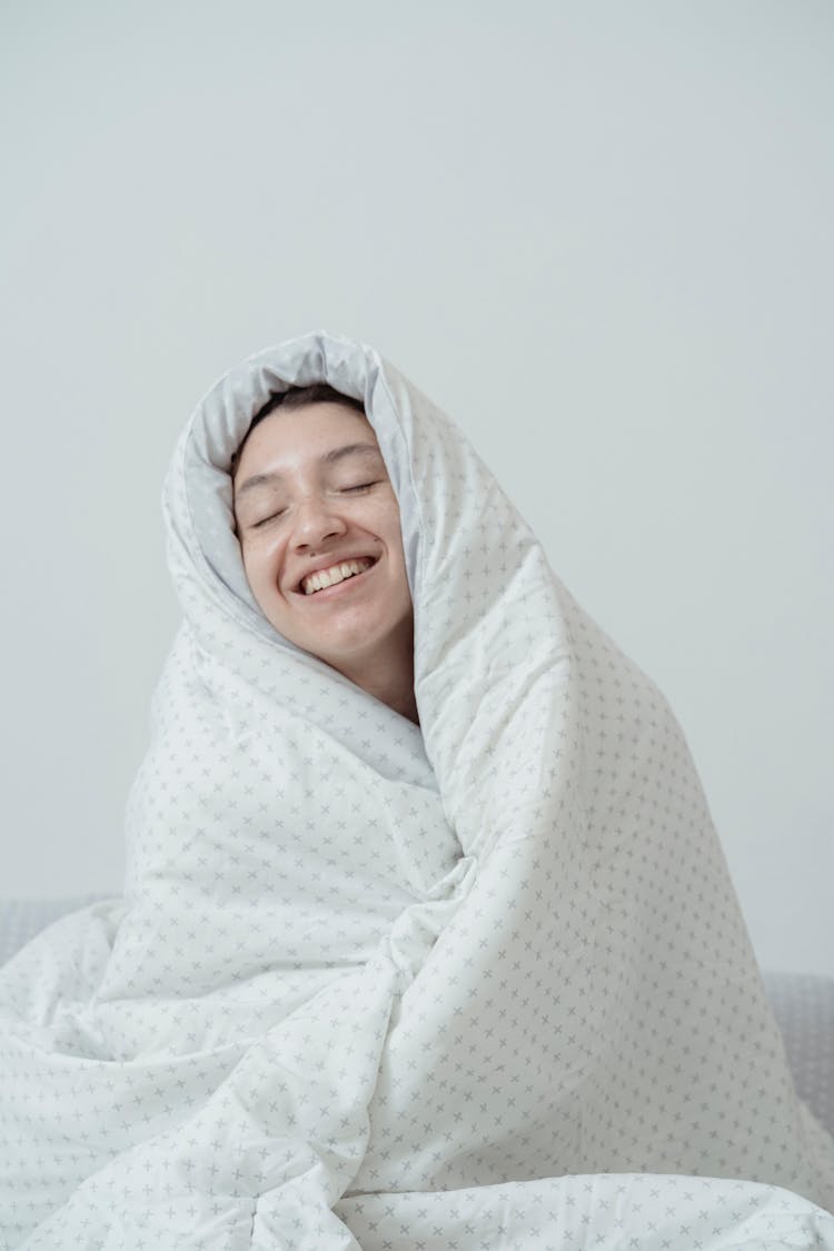 Happy Woman Wrapped In Bed Covers