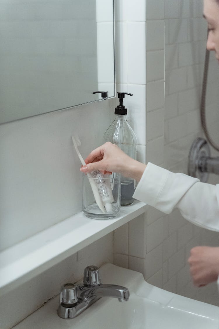 Woman Picking Up Toothbrush From Cup